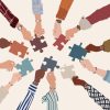 Group of multicultural business people with arms and hands in a circle holding a piece of jigsaw. Co workers of diverse ethnic groups and cultures. Cooperate collaborate. Teamwork